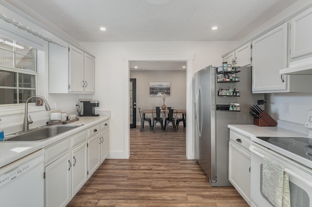 kitchen with white appliances, wood-type flooring, a textured ceiling, white cabinets, and sink