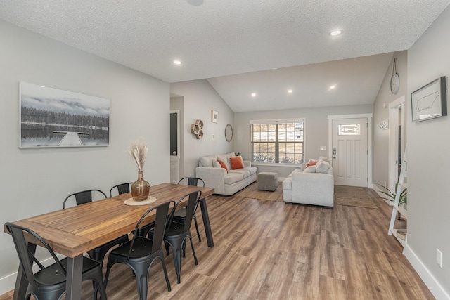 dining room featuring a textured ceiling, lofted ceiling, and hardwood / wood-style flooring