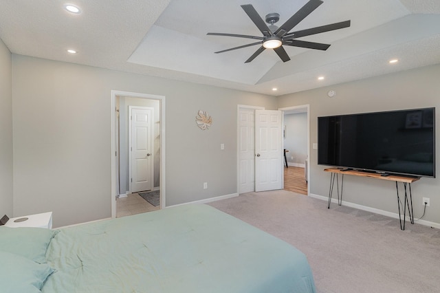 bedroom with ceiling fan, a raised ceiling, light carpet, and vaulted ceiling