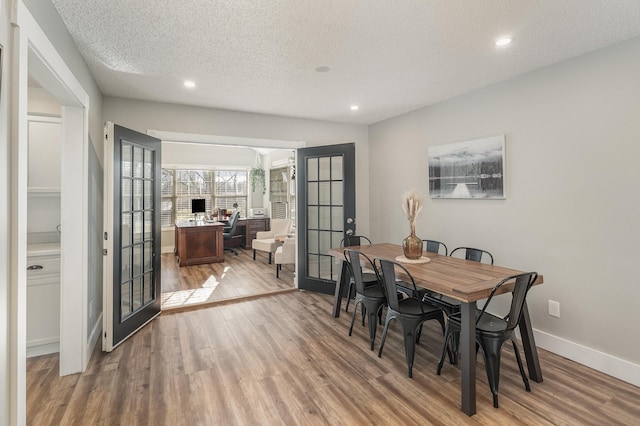 dining room featuring french doors, a textured ceiling, and light hardwood / wood-style flooring