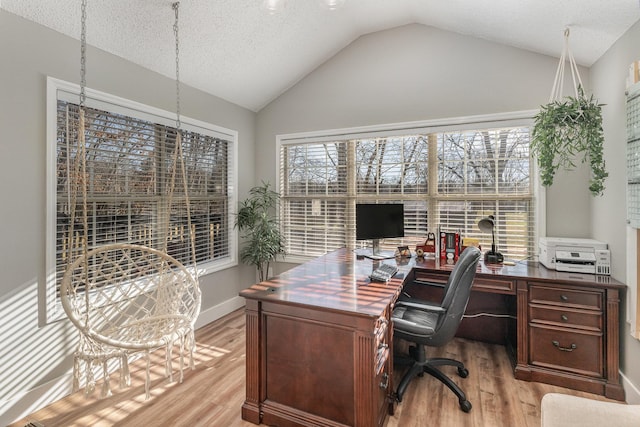 office area with vaulted ceiling, a textured ceiling, and light wood-type flooring