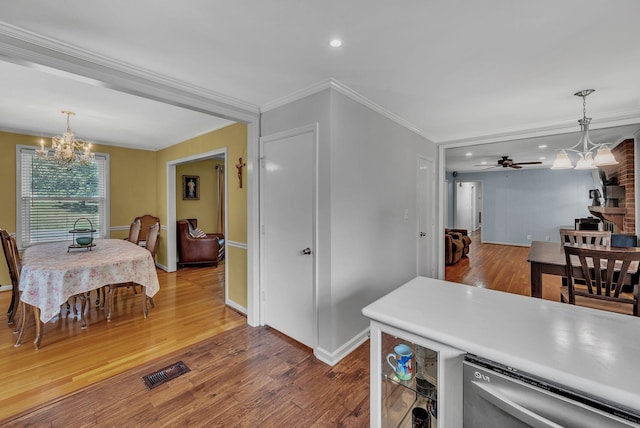 kitchen with crown molding, ceiling fan with notable chandelier, wood-type flooring, and decorative light fixtures