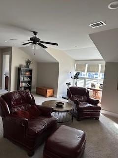 carpeted living room with ceiling fan and vaulted ceiling