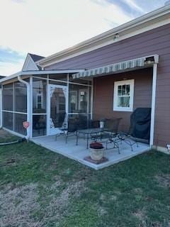 back of property with a sunroom, a lawn, and a patio