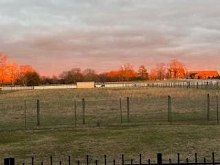 yard at dusk featuring a rural view