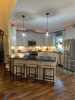 kitchen featuring kitchen peninsula, pendant lighting, stainless steel appliances, and a kitchen bar