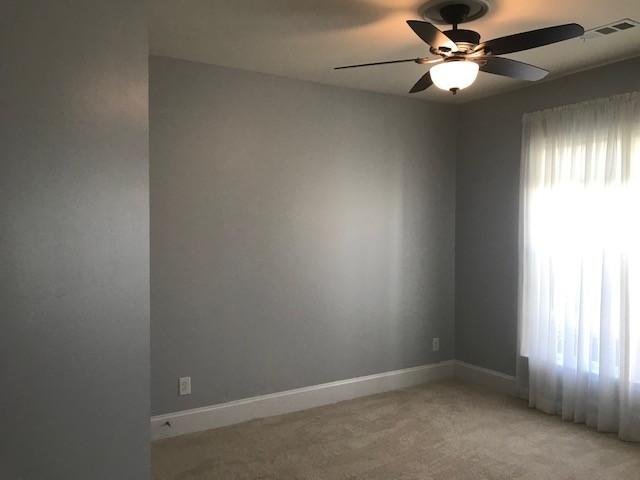 carpeted spare room with ceiling fan