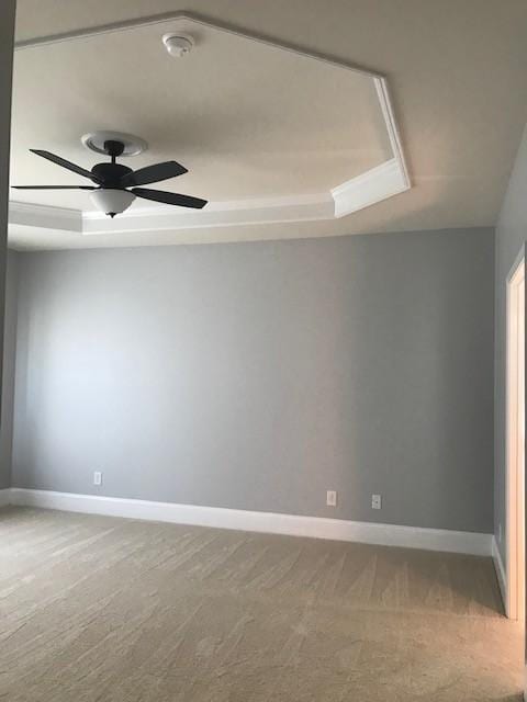 unfurnished room featuring a raised ceiling, carpet flooring, and ceiling fan