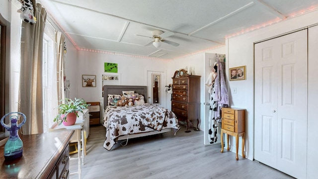 bedroom with ceiling fan, light hardwood / wood-style flooring, and a closet