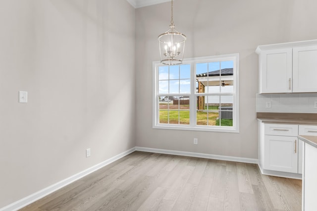 unfurnished dining area with an inviting chandelier and light hardwood / wood-style floors