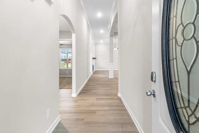 hall with ornamental molding and light wood-type flooring