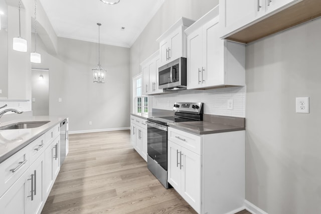 kitchen featuring appliances with stainless steel finishes, decorative backsplash, pendant lighting, white cabinets, and sink