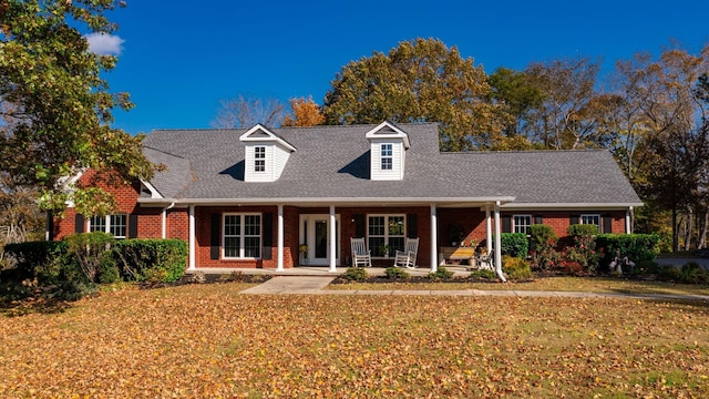 new england style home featuring covered porch and a front lawn