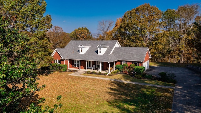 new england style home featuring a porch, a garage, and a front lawn