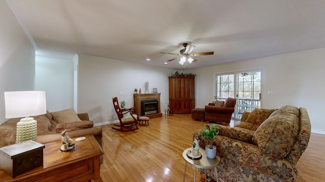 living room with ornamental molding, ceiling fan, and light wood-type flooring