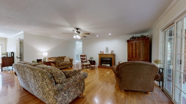 living room featuring ceiling fan, ornamental molding, and light hardwood / wood-style floors