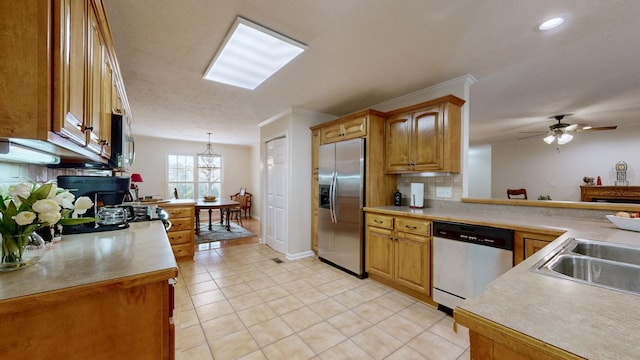 kitchen with sink, hanging light fixtures, appliances with stainless steel finishes, kitchen peninsula, and backsplash