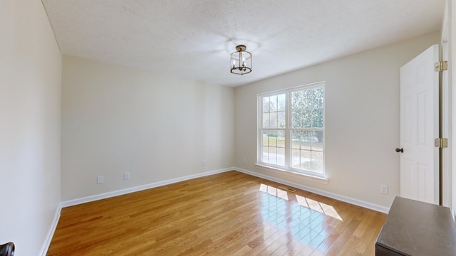 empty room with a textured ceiling and light wood-type flooring