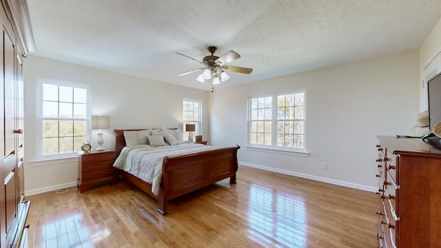 bedroom with a textured ceiling, ceiling fan, and light hardwood / wood-style flooring