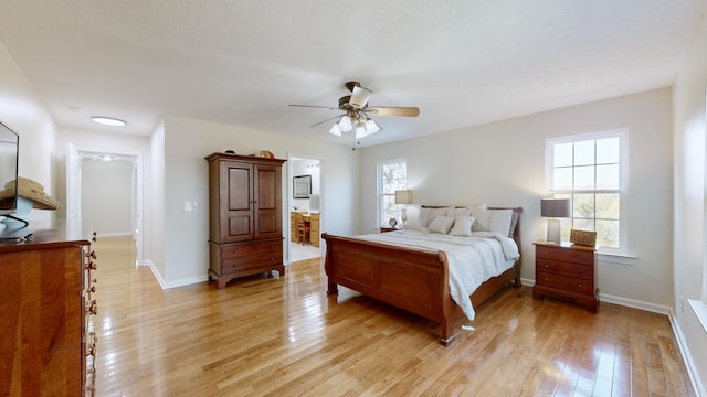 bedroom with multiple windows, ceiling fan, light hardwood / wood-style floors, and ensuite bath