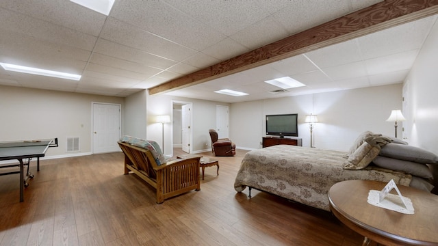 bedroom featuring wood-type flooring and a drop ceiling