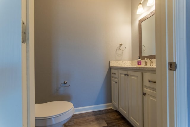 bathroom with wood-type flooring, toilet, and vanity