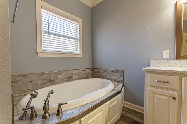 bathroom with vanity, ornamental molding, hardwood / wood-style flooring, and a tub