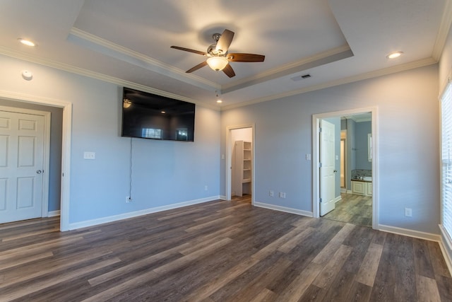 unfurnished bedroom with ceiling fan, dark hardwood / wood-style floors, a tray ceiling, a closet, and a walk in closet