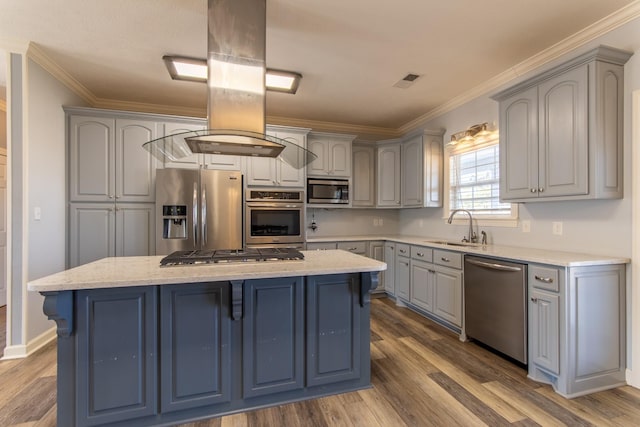 kitchen with a center island, stainless steel appliances, sink, gray cabinets, and ornamental molding