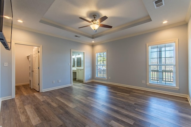 unfurnished bedroom featuring ornamental molding, connected bathroom, a tray ceiling, and multiple windows