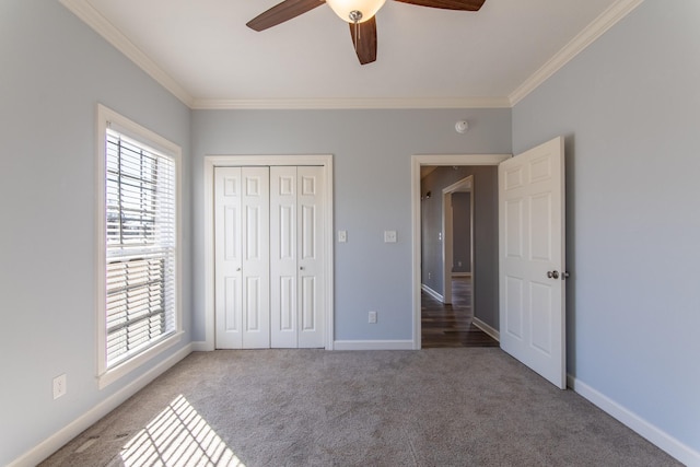 unfurnished bedroom with ceiling fan, a closet, crown molding, and carpet flooring