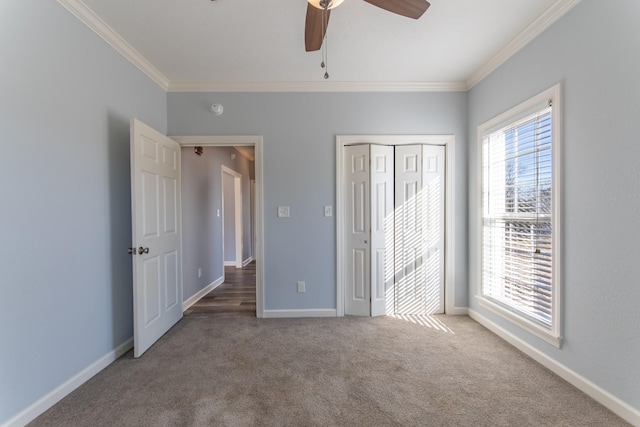 unfurnished bedroom featuring ceiling fan, carpet, crown molding, and a closet