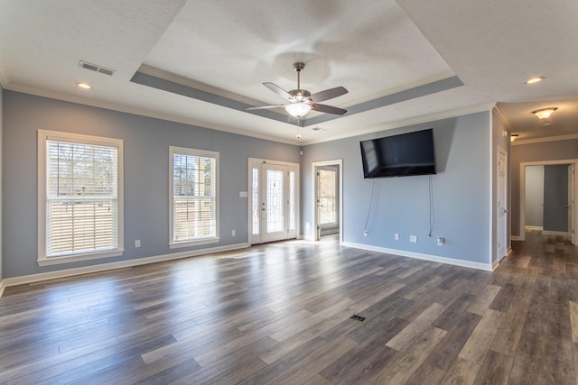 empty room with dark wood-type flooring, a tray ceiling, and crown molding