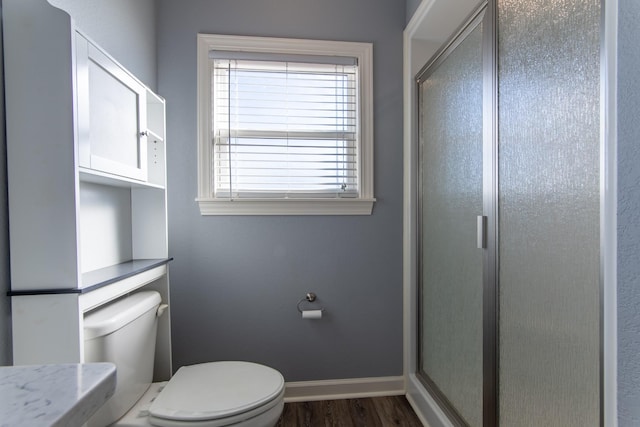 bathroom with hardwood / wood-style flooring, toilet, and a shower with door