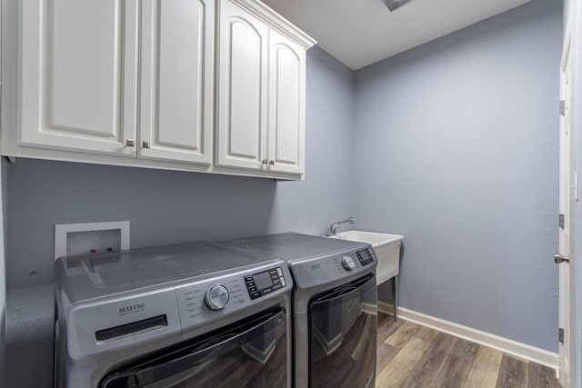 laundry area featuring dark wood-type flooring, sink, separate washer and dryer, and cabinets