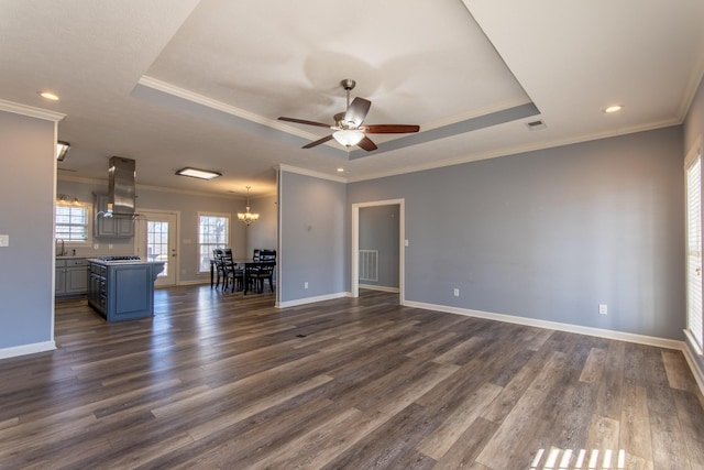 unfurnished living room with crown molding, ceiling fan with notable chandelier, and a tray ceiling