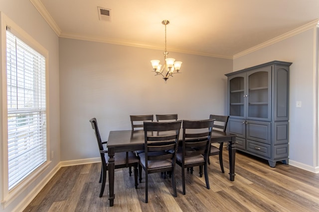 dining space featuring dark wood-type flooring, a notable chandelier, and crown molding