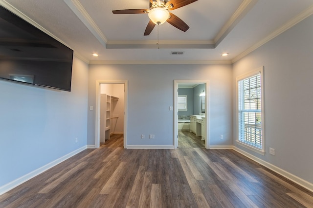 unfurnished bedroom with a spacious closet, a closet, connected bathroom, and a raised ceiling