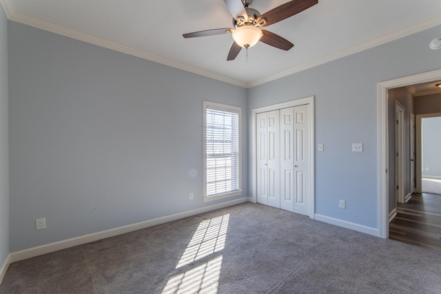 unfurnished bedroom with ceiling fan, a closet, crown molding, and dark colored carpet