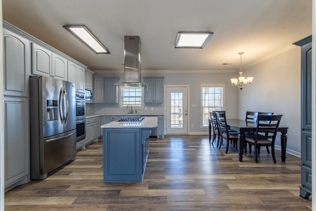 kitchen with a notable chandelier, pendant lighting, a center island, island exhaust hood, and appliances with stainless steel finishes