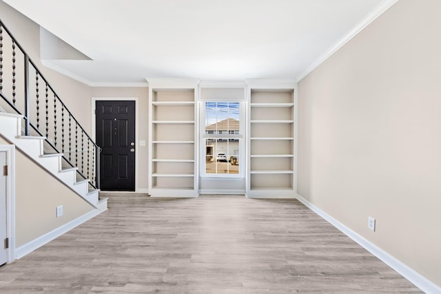 entryway with ornamental molding and light hardwood / wood-style flooring