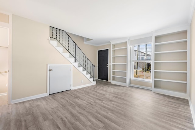 unfurnished living room featuring built in features, light hardwood / wood-style flooring, and ornamental molding