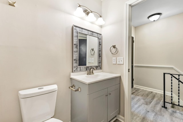 bathroom with toilet, hardwood / wood-style floors, and vanity