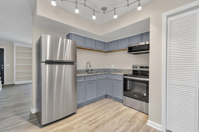 kitchen with light stone countertops, appliances with stainless steel finishes, light hardwood / wood-style floors, sink, and gray cabinets