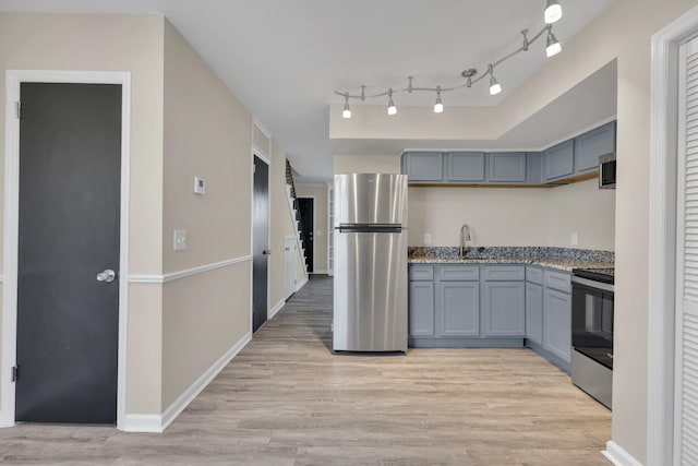 kitchen with gray cabinets, sink, light hardwood / wood-style flooring, appliances with stainless steel finishes, and light stone counters