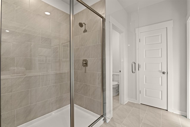 bathroom featuring tile patterned floors, toilet, and an enclosed shower