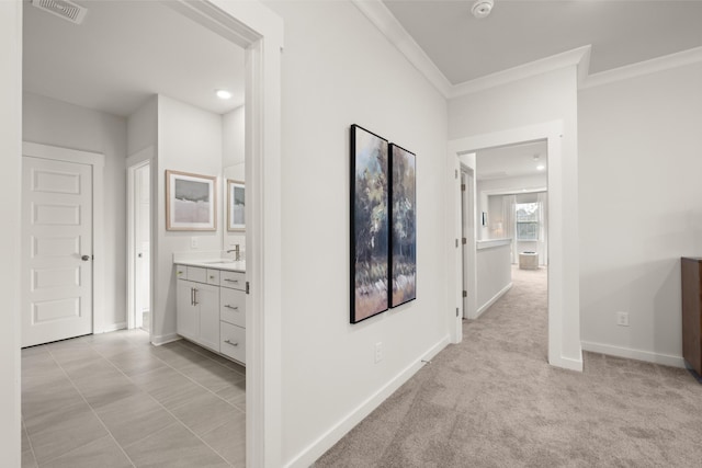 hall featuring crown molding, light colored carpet, and sink