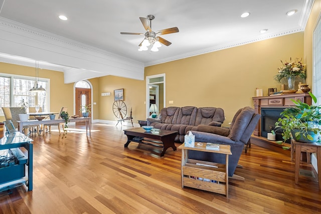 living room featuring light wood-type flooring, ceiling fan, and crown molding