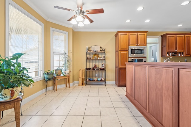 kitchen with ceiling fan, light tile patterned floors, appliances with stainless steel finishes, and ornamental molding