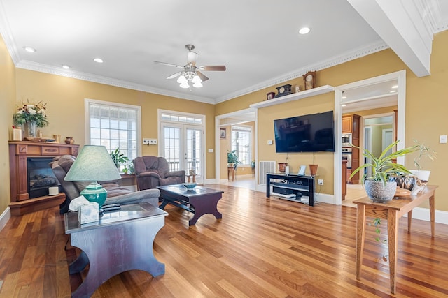 living room featuring ceiling fan, hardwood / wood-style flooring, ornamental molding, and french doors